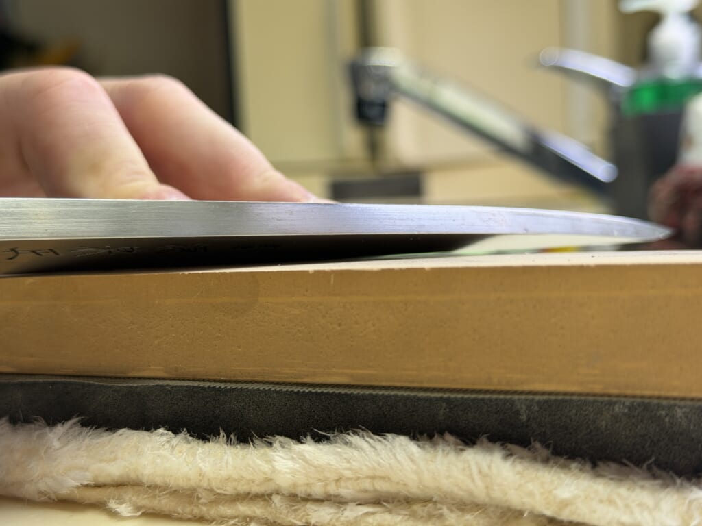 出刃包丁を砥石に当てて研ぐ際の角度を横から撮影した写真