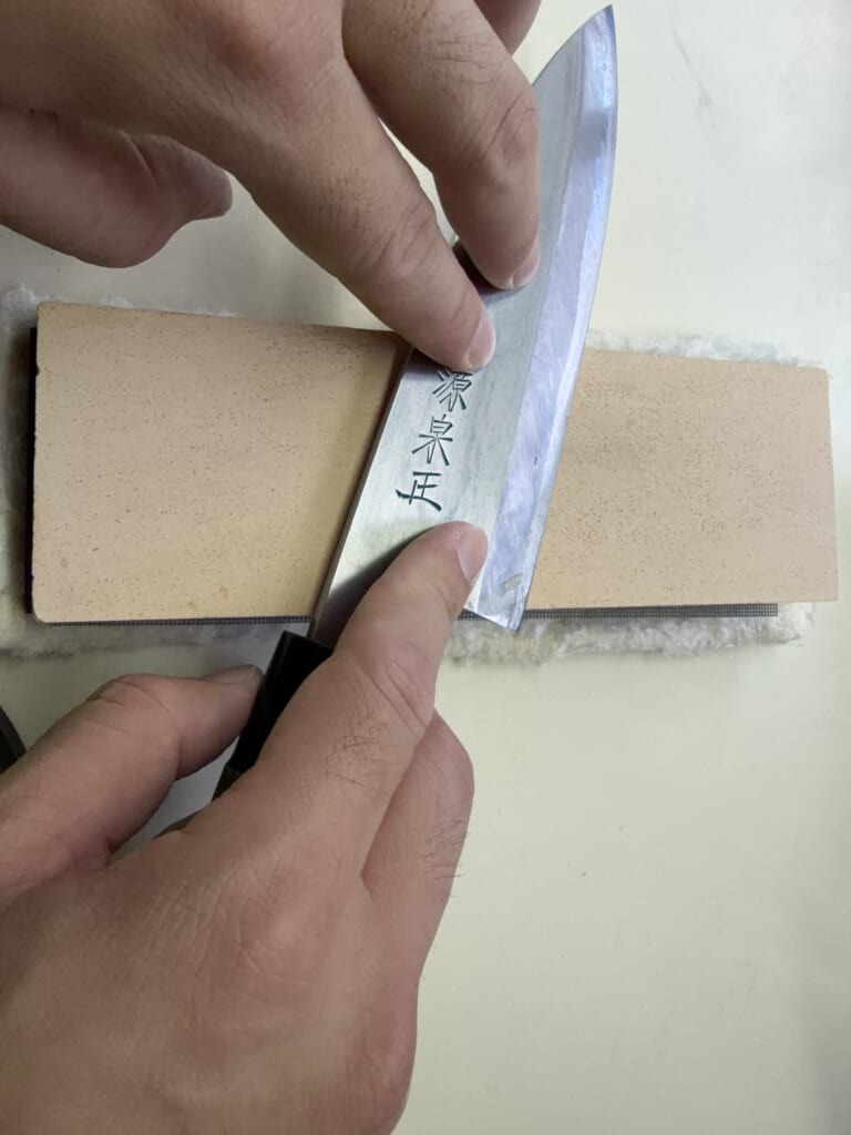 出刃包丁の裏側を砥石に平らに当てて裏押ししている様子